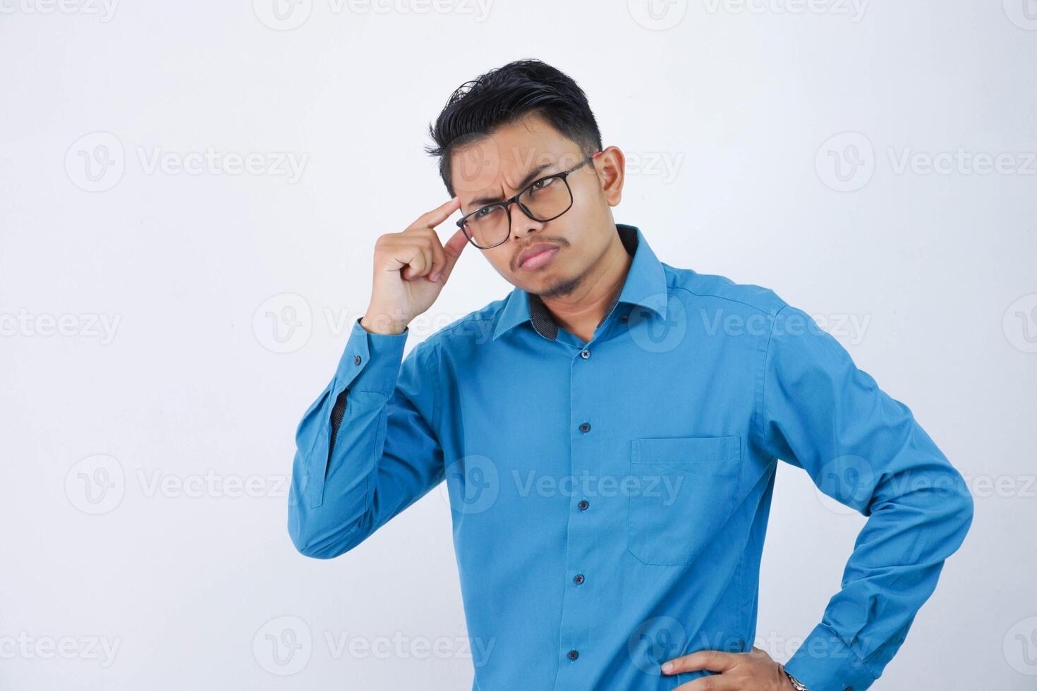 joven hermoso asiático hombre con lentes pensando y mirando para ideas vistiendo azul camisa aislado en blanco antecedentes foto