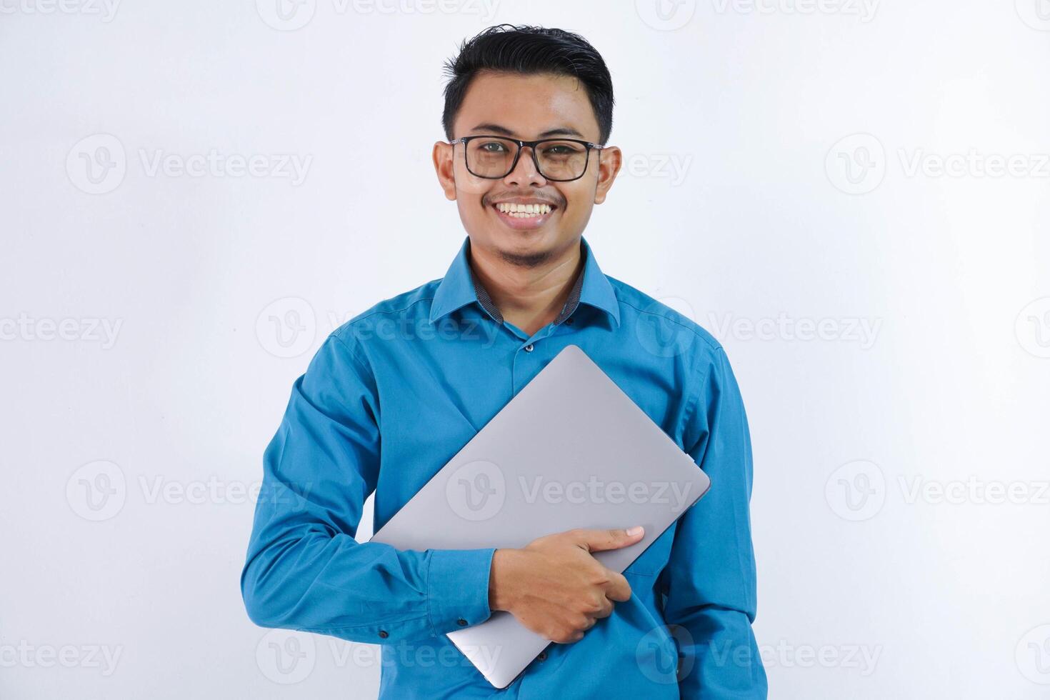 smiling or happy asian businessman with glasses holding laptop wearing blue shirt isolated on white background photo