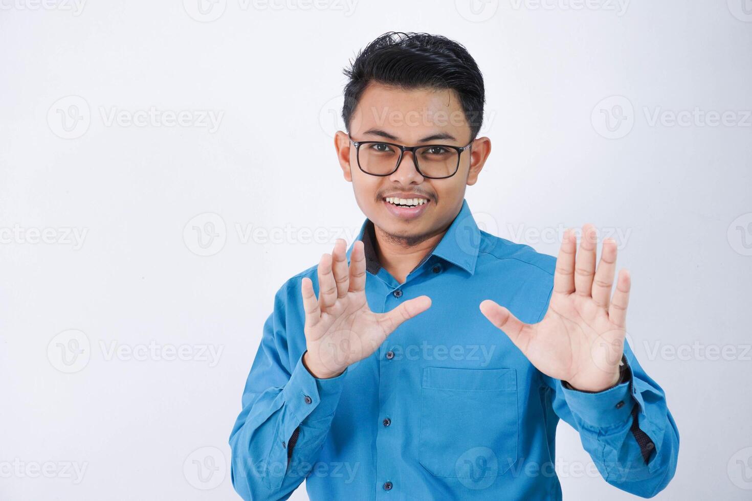 disgustado hermoso joven asiático empresario con lentes en vistiendo azul camisa demostración detener firmar aislado en blanco antecedentes foto