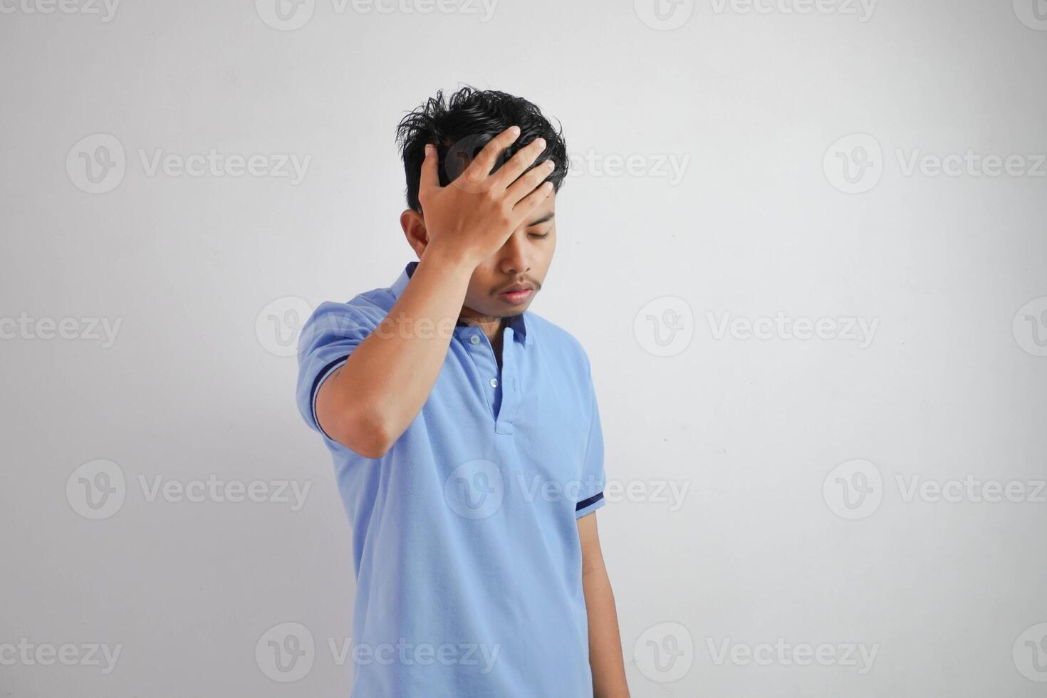 dizziness or stress portrait young asian man holding head wearing blue polo t shirt isolated on white background photo
