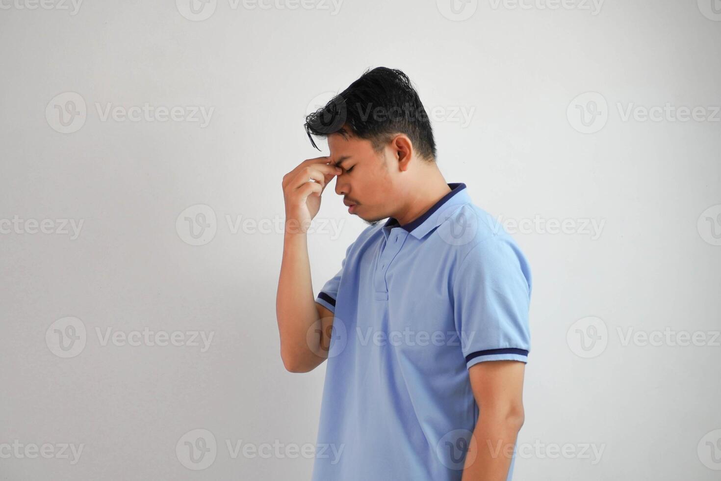 dizziness or depression portrait young asian man holding nose wearing blue polo t shirt isolated on white background photo