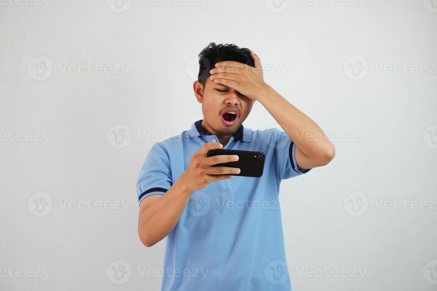 young asian man the effect of being disappointed when you lose playing a game online with smartphone and holding your forehead isolated on white background photo