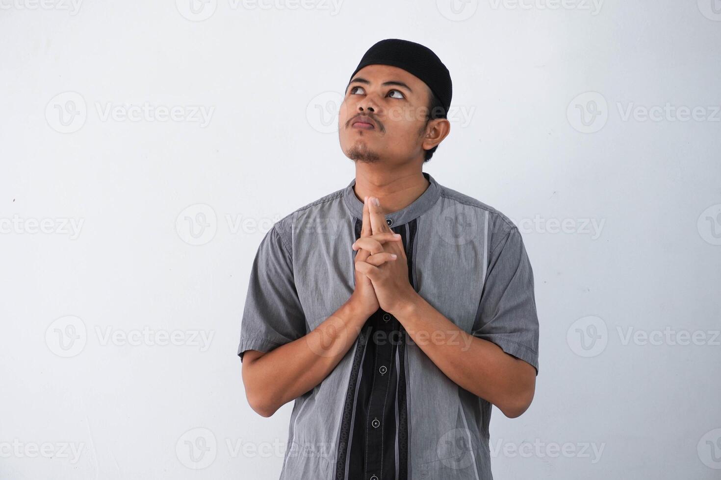 thinking young asian muslim man looking up thinking gesture, looking for idea wearing grey muslim clothes isolated on white background photo