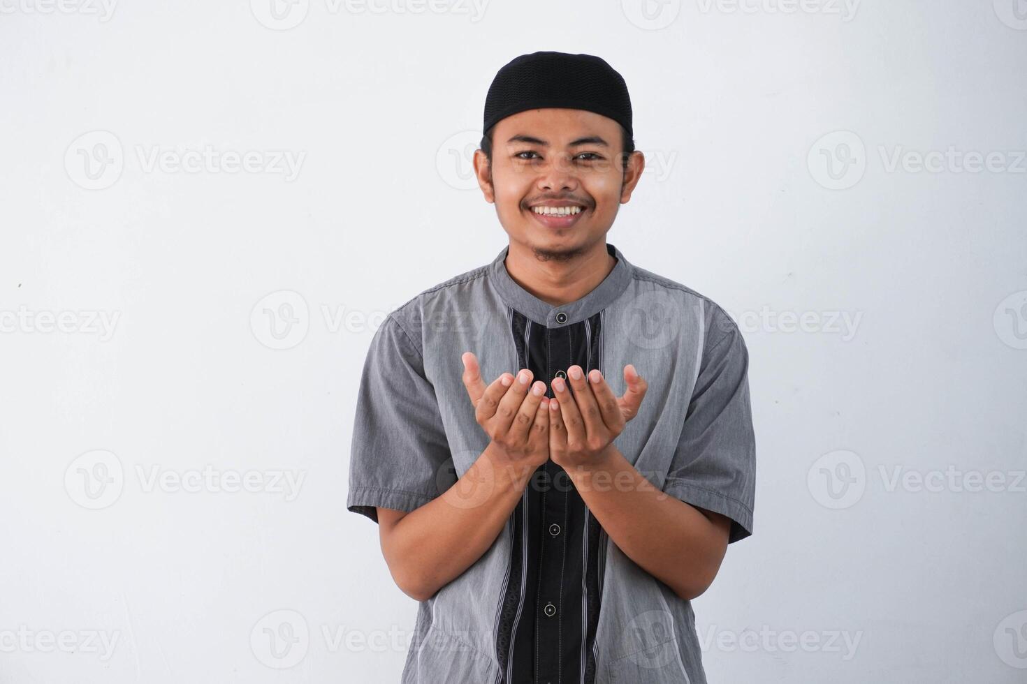 Religious young asian muslim man with open eyes praying, holding palms face up, whispering pray, isolated on white background. Religion islam, believing concept photo