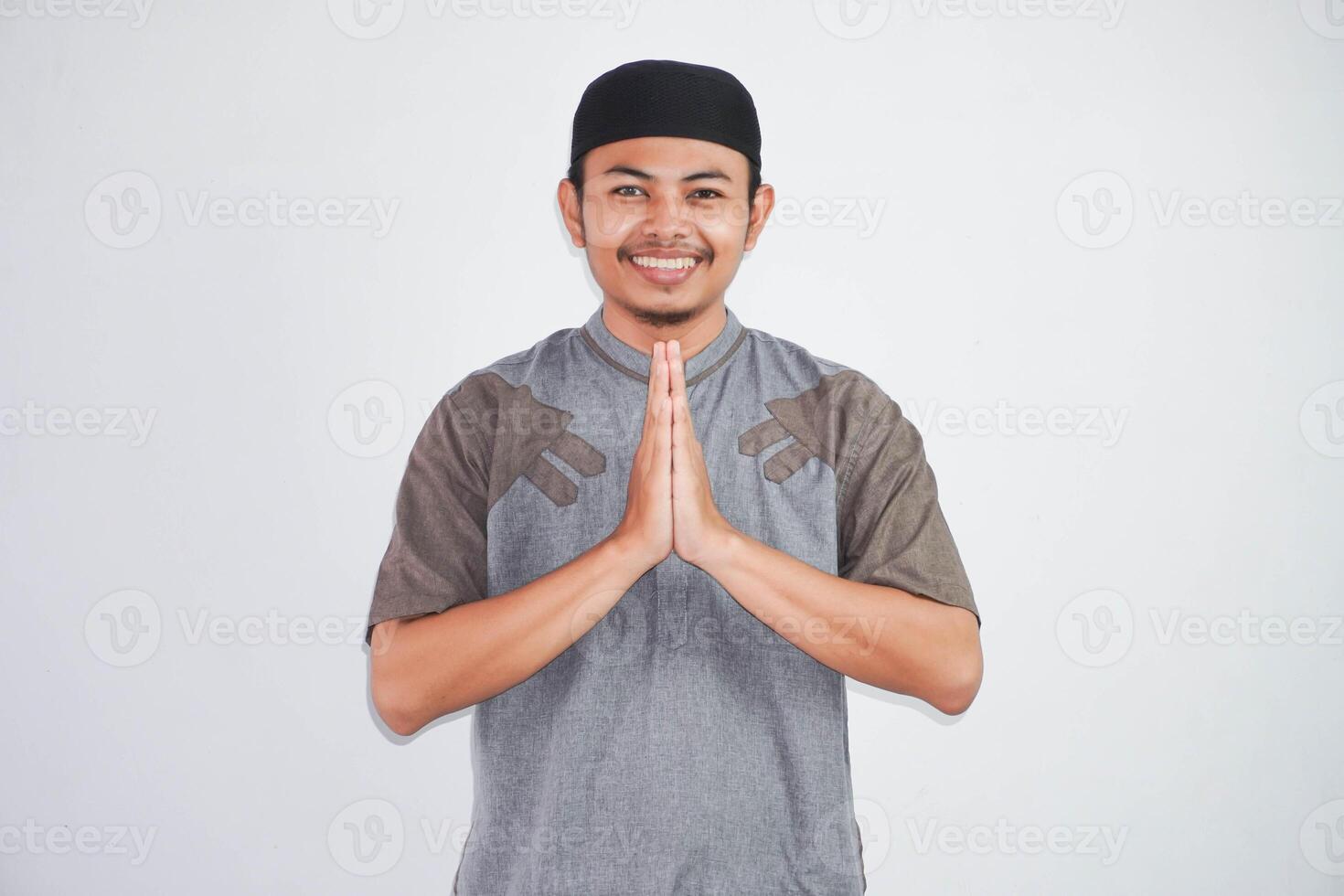 young Asian Muslim man wearing koko clothes smiling to give greeting during Ramadan and Eid Al Fitr celebration isolated on white background photo