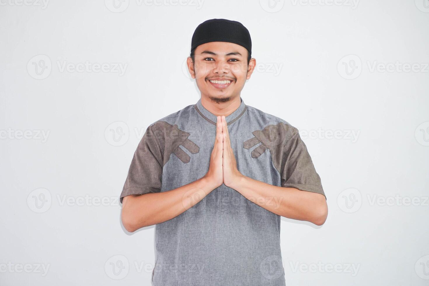 young Asian Muslim man wearing koko clothes smiling to give greeting during Ramadan and Eid Al Fitr celebration isolated on white background photo