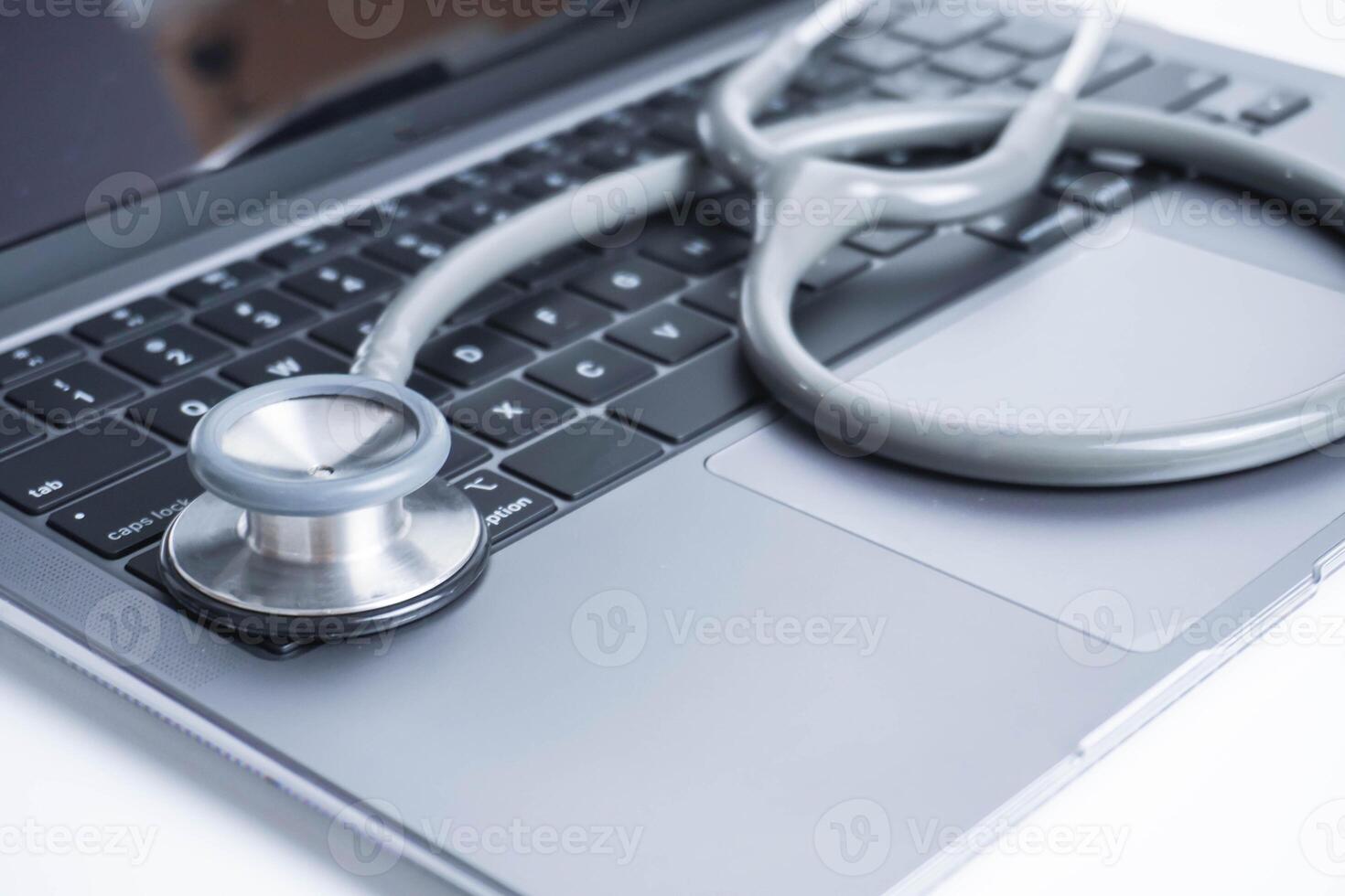 Closeup Grey Stethoscope on laptop keyboard. Health care or IT security concept. photo