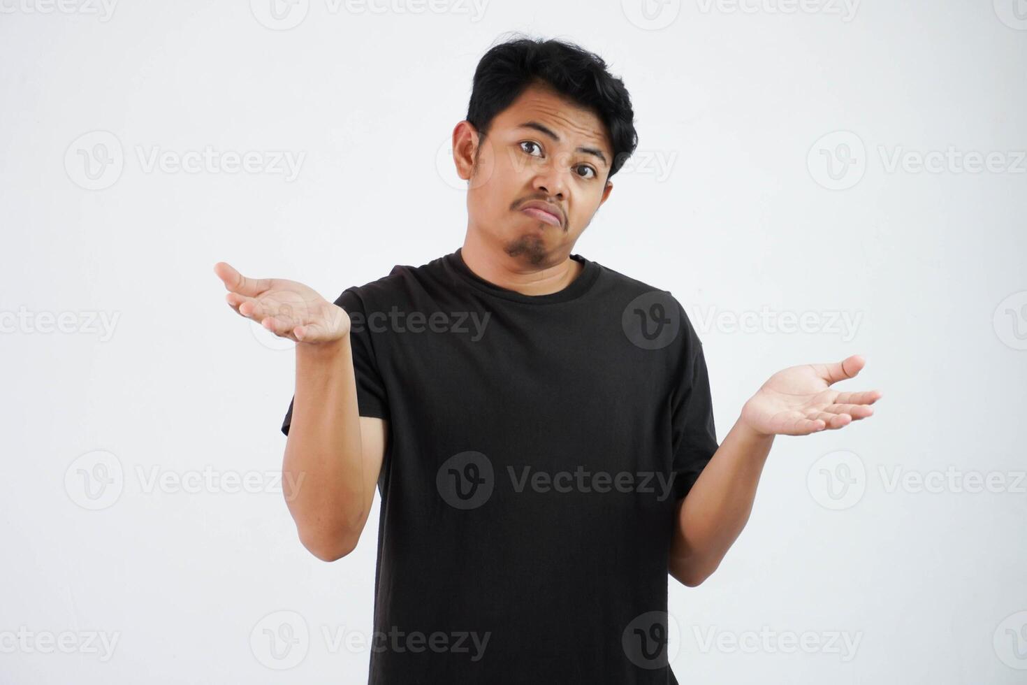 Handsome young asian man wearing black t shirt show hands up confused i don't know isolated on white background photo