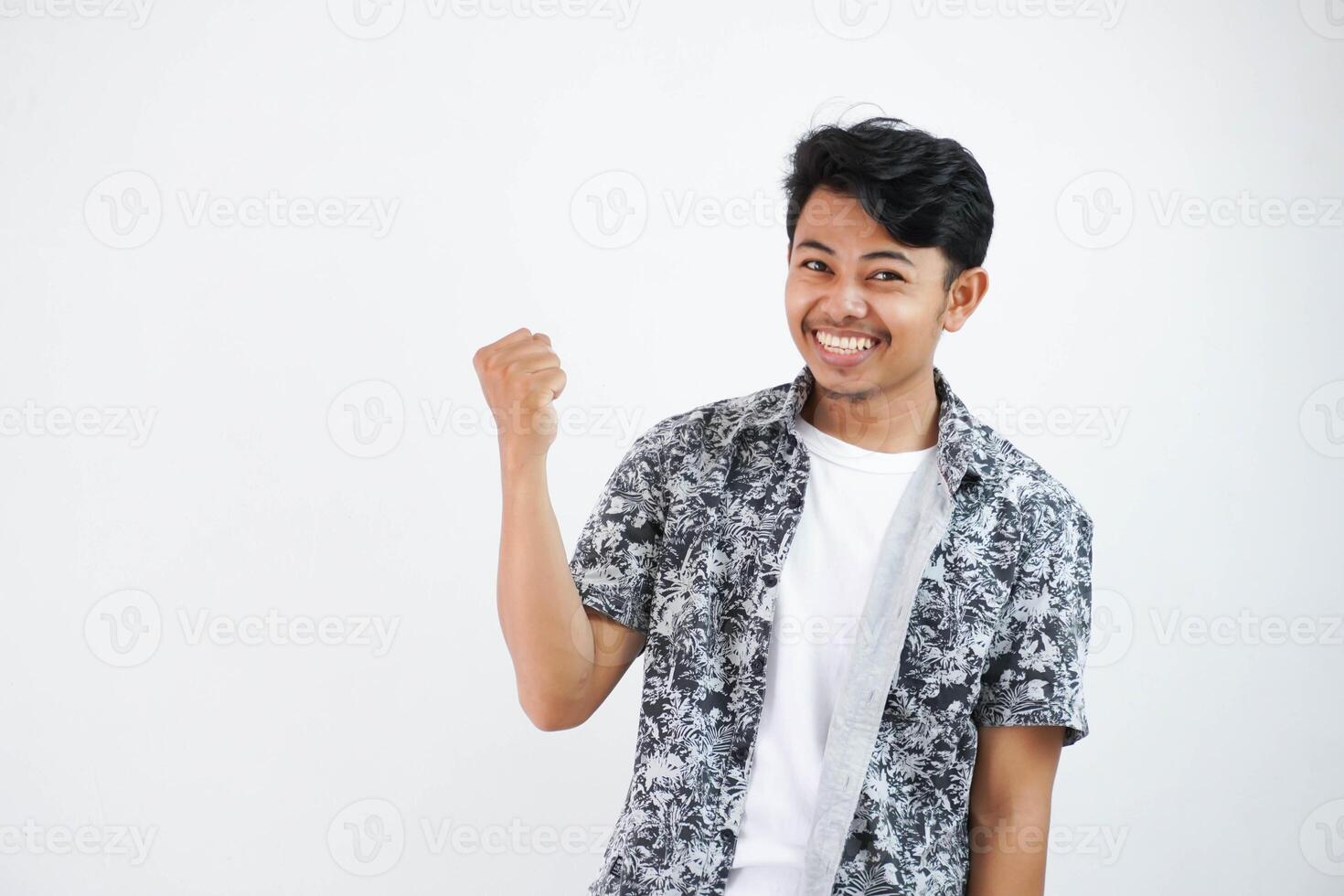 Confident cheerful handsome asian man lifting hands up wearing black shirt feels happiness show fist up success isolated on white background photo