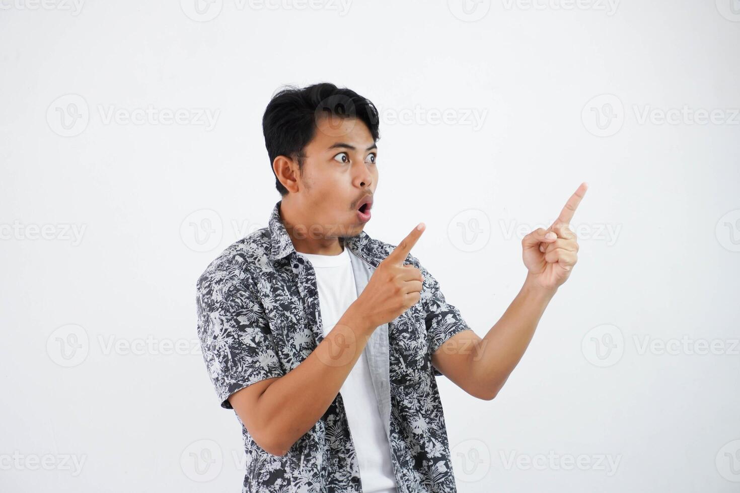 shocked asian man with fingers pointing to the side wearing black shirt isolated on white background photo