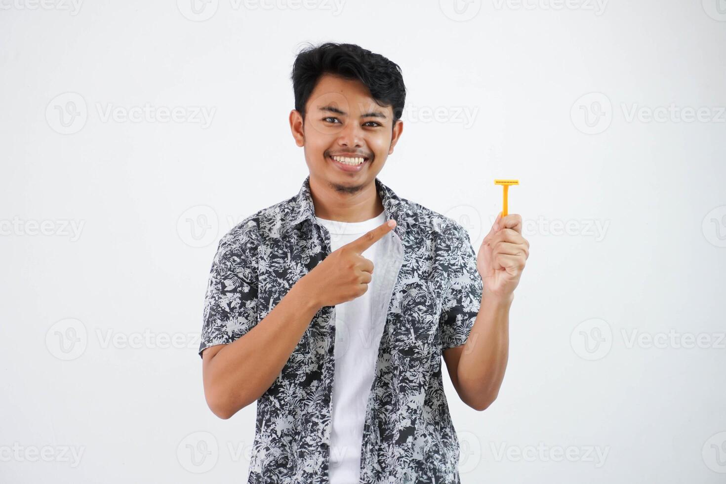 smiling or happy young asian man pointing at the shaver with his finger wearing black shirt isolated on white background photo