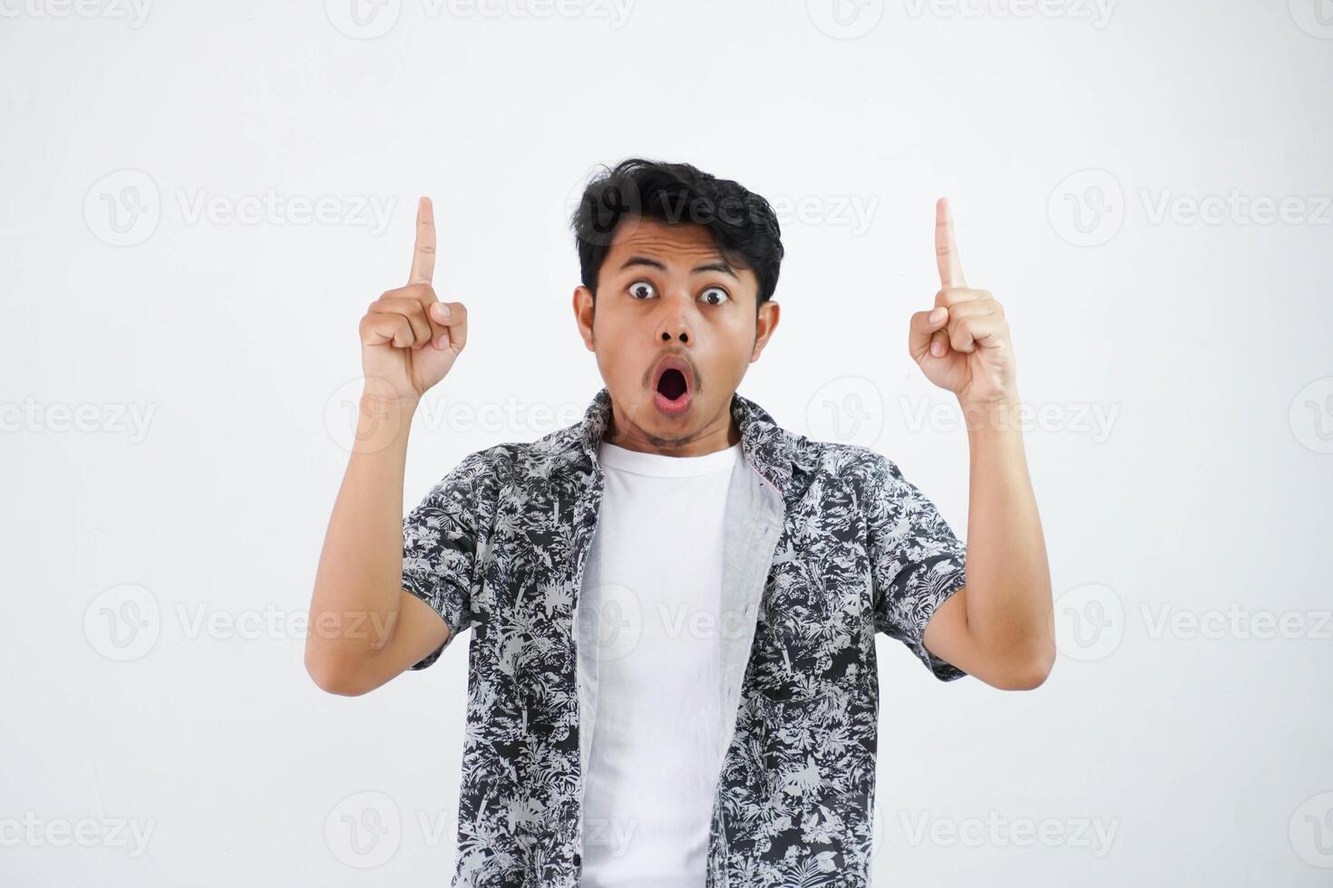 shock young Asian man pointing up with big eyes and mouth open, shocked surprised expression isolated photo