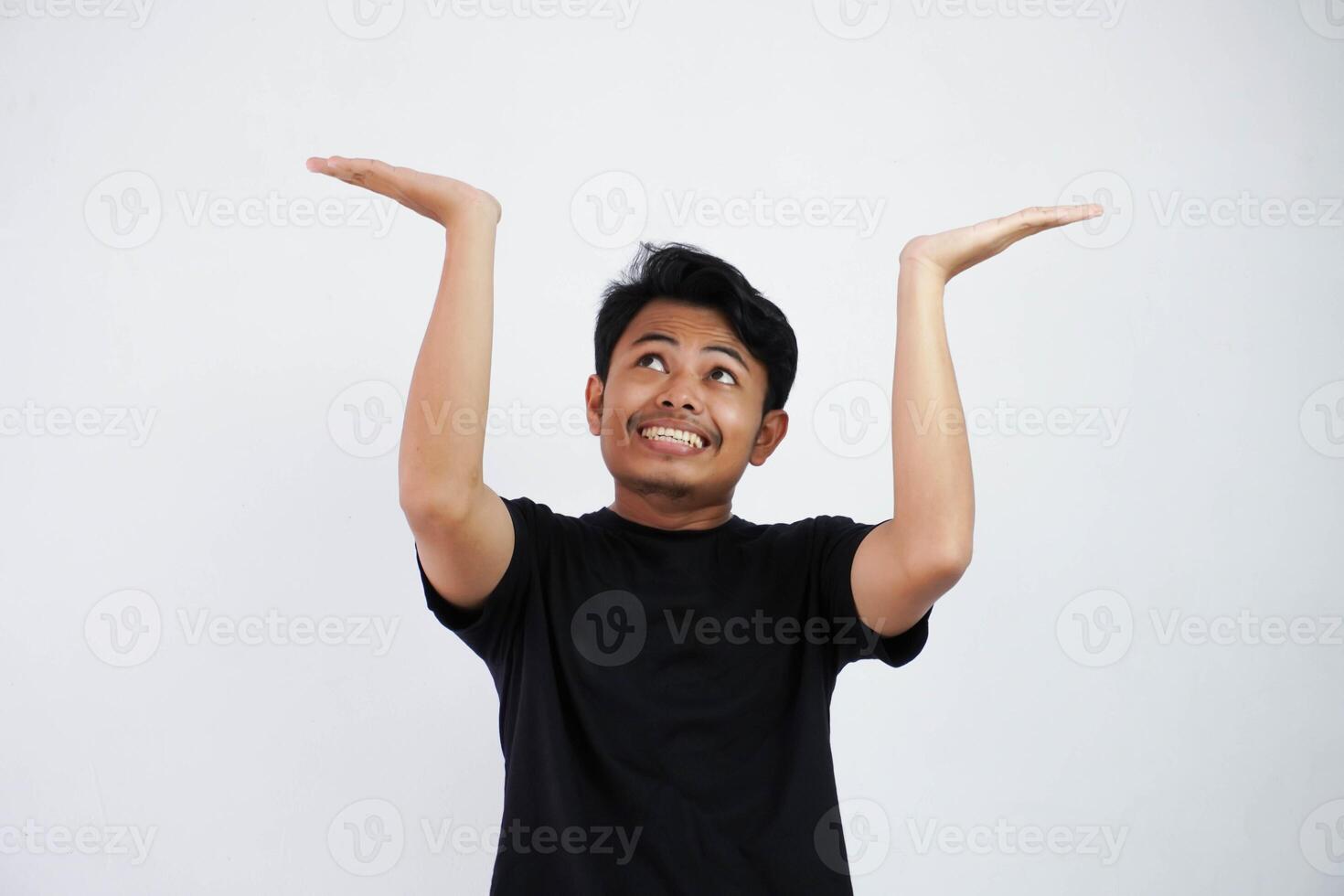 Young Asian man in black casual clothes attempt to hold something heavy from above. isolated on white background photo