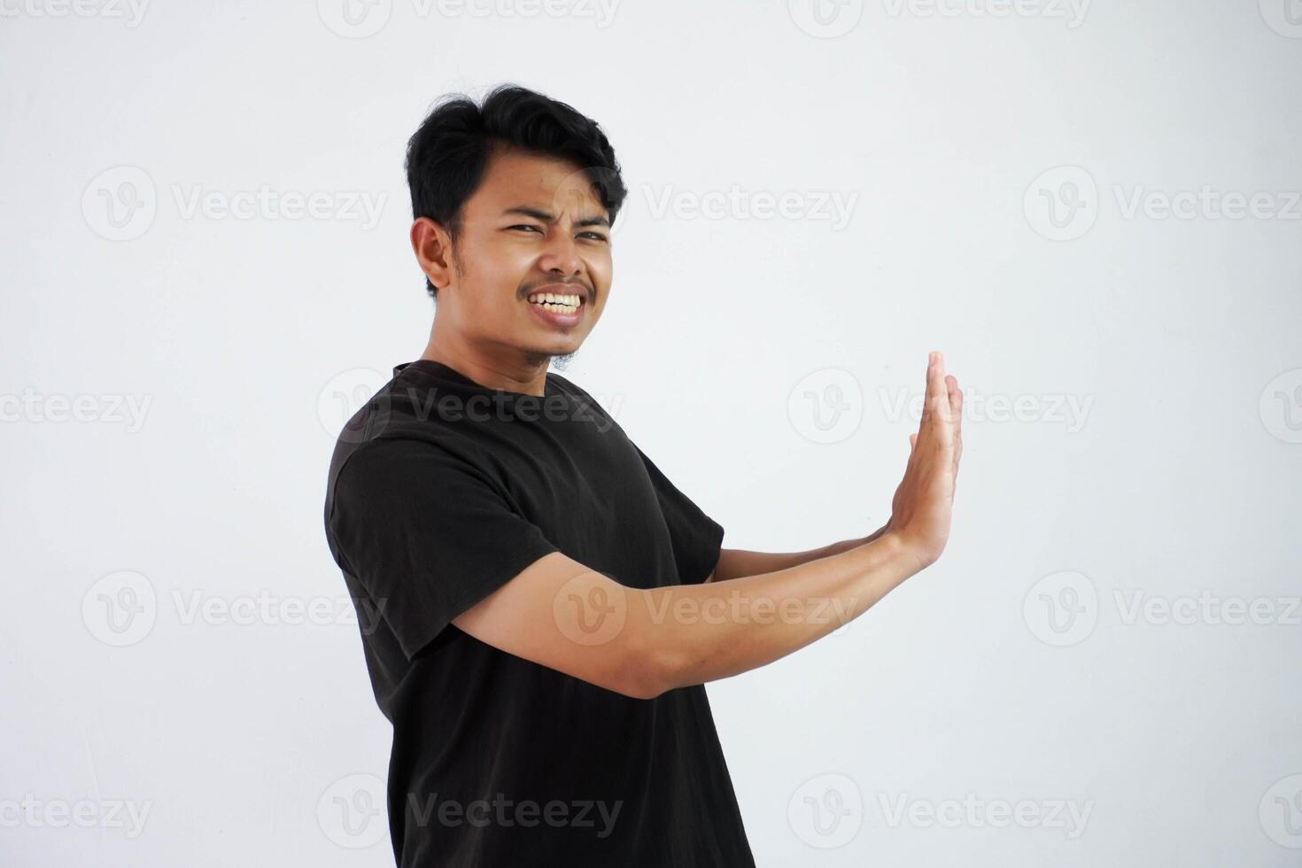 Young asian man wearing black t shirt gesture push his hands feels heavy isolated on white background photo