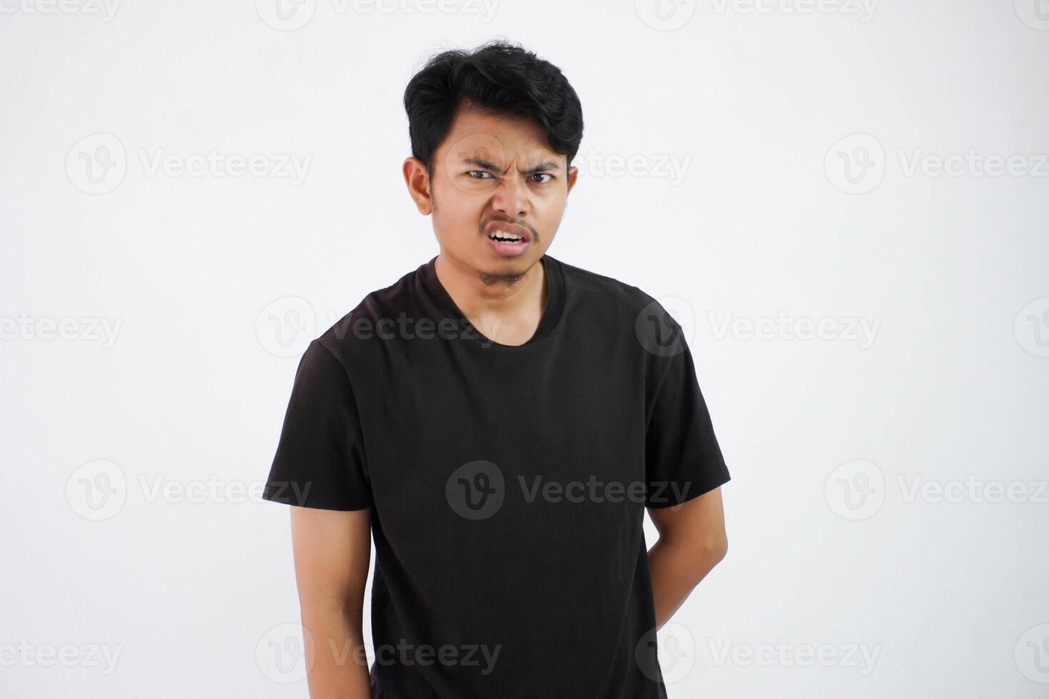 irritado joven asiático hombre vistiendo negro t camisa estar duda cara siente mareado aislado en blanco antecedentes foto