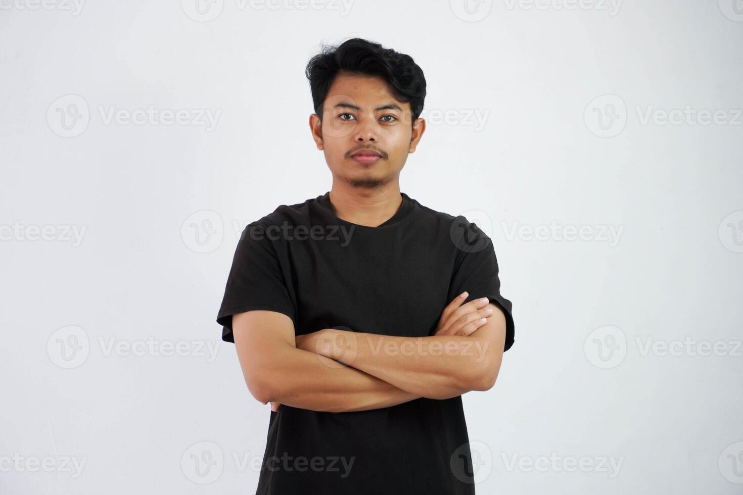 seriamente asiático hombre cruzado brazos y mirando cámara vistiendo negro t camisa aislado en blanco antecedentes foto