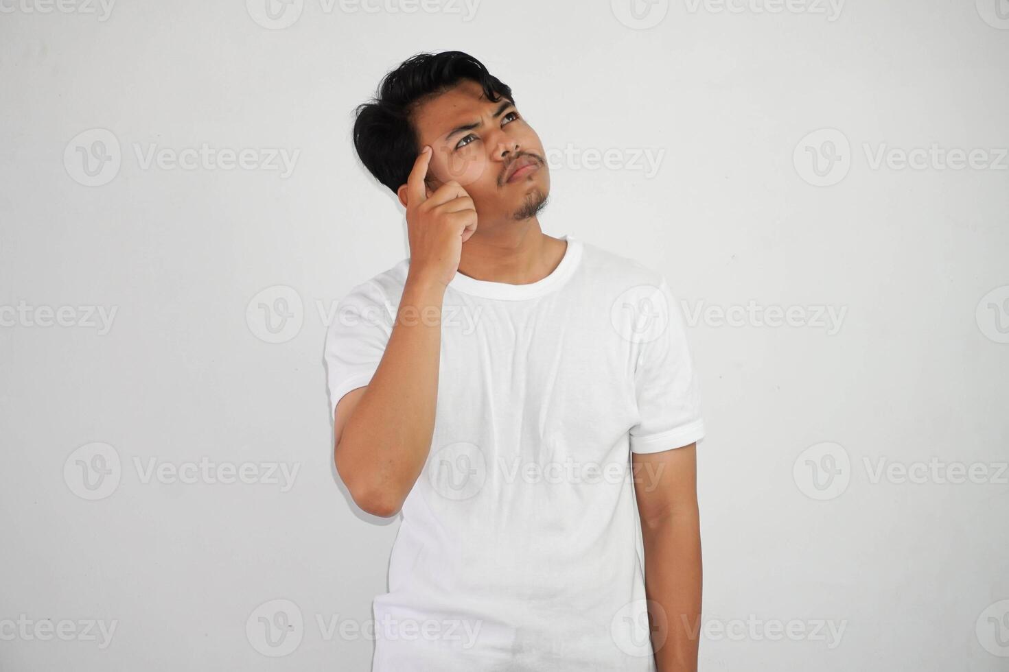 pensando joven asiático hombre señalando cabeza pensando gesto, mirando para idea vistiendo blanco t camisa aislado en blanco antecedentes foto