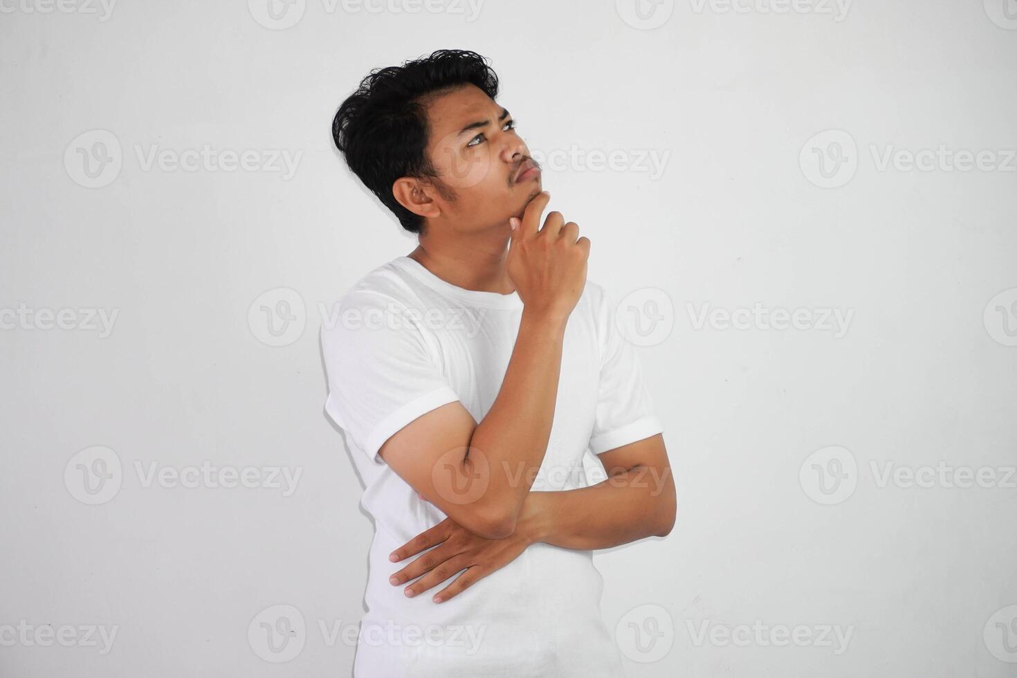 thinking young asian man holding chin thinking gesture, looking for idea wearing white t shirt isolated on white background photo