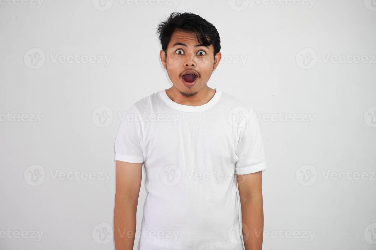 Close up of shocked young Asian man with open mouth and looking at camera wearing white t shirt isolated on white background photo