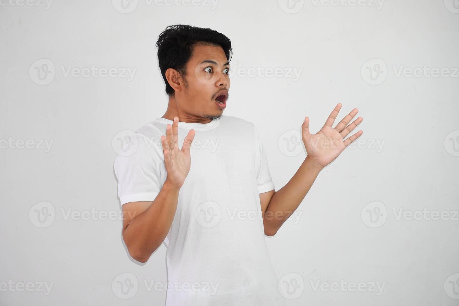 shock asian man with open hands and mouth wearing white t shirt isolated on white background photo
