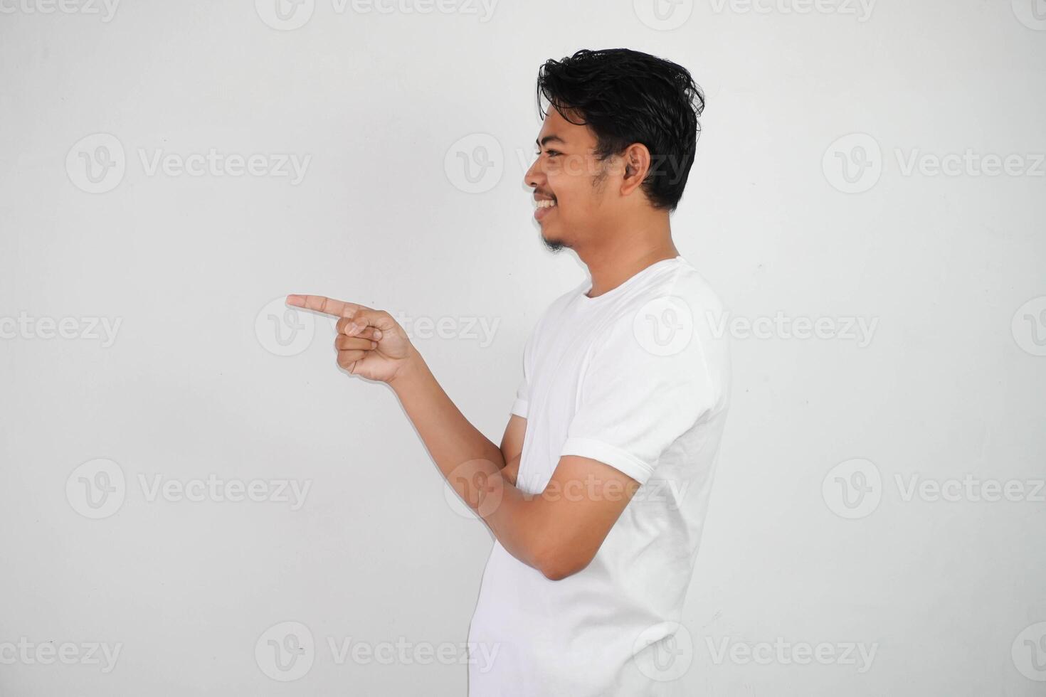smiling asian man with fingers pointing to the side wearing white t shirt isolated on white background photo