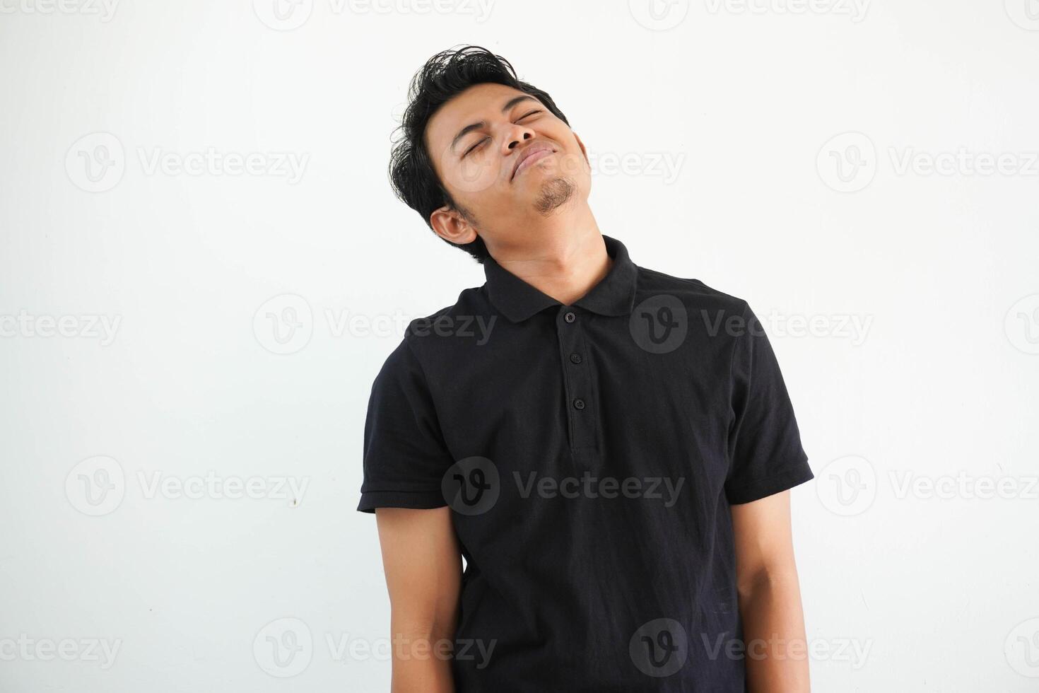 joven asiático asiático hombre relajado y contento reír, cuello estirado demostración dientes vistiendo negro polo t camisa aislado uno blanco antecedentes foto