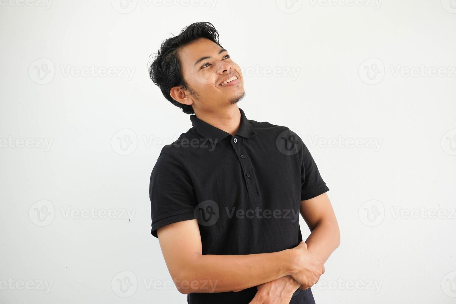 joven asiático asiático hombre relajado y contento reír, cuello estirado demostración dientes vistiendo negro polo t camisa aislado uno blanco antecedentes foto