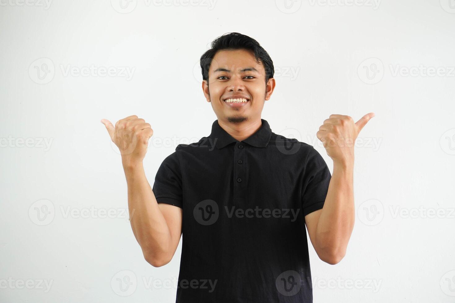 sonriente asiático hombre pulgar señalando ti el Derecha y izquierda lado, confuso a escoger alguna cosa vistiendo negro polo t camisa aislado en blanco antecedentes foto