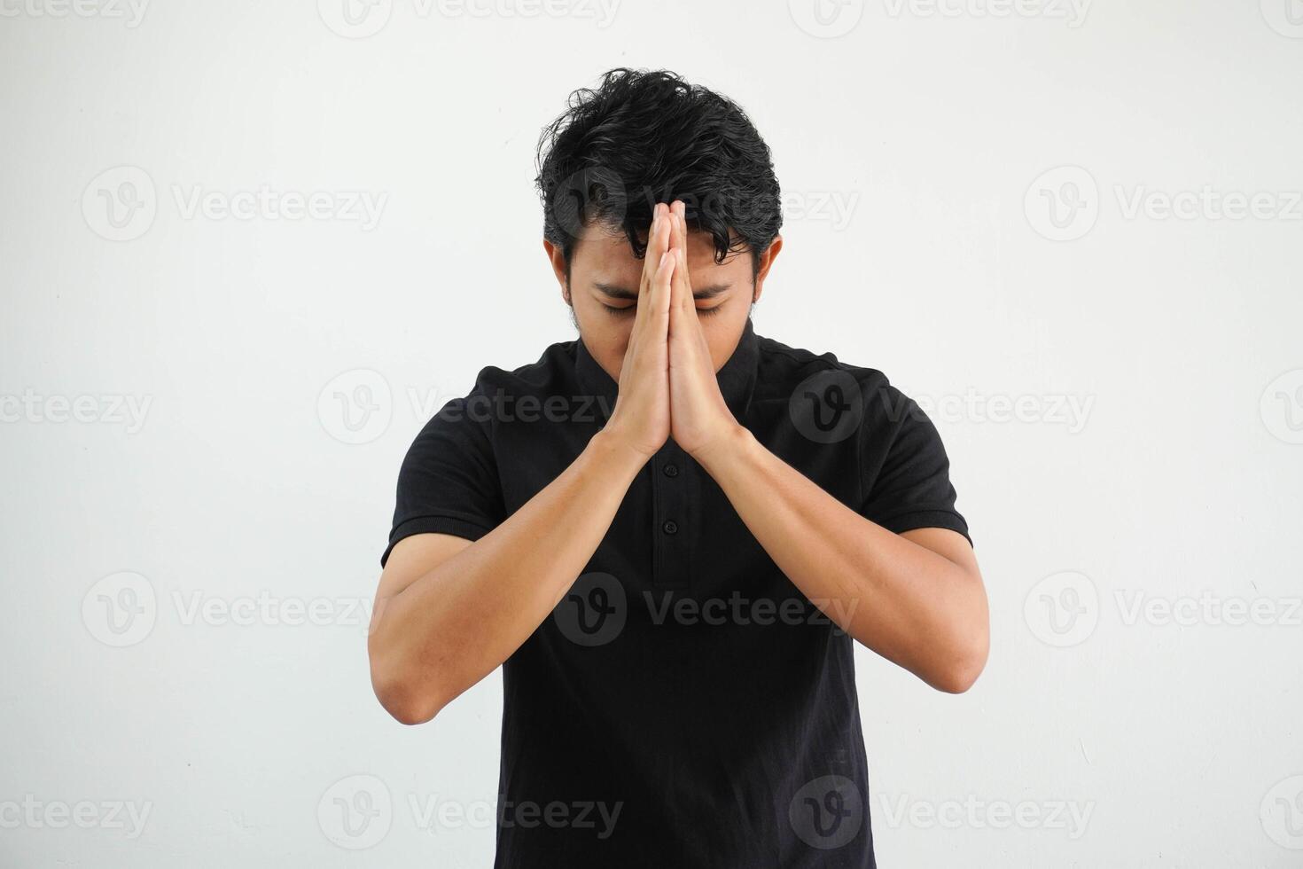 Portrait of moslem asian man wearing black polo t shirt with both hands giving greeting isolated on white background photo