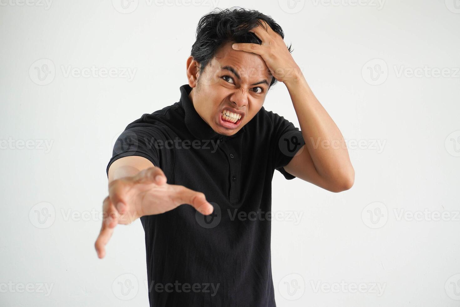 retrato de enojado pensativo loco asiático joven hombre gritando vistiendo negro polo t camisa aislado en blanco antecedentes foto