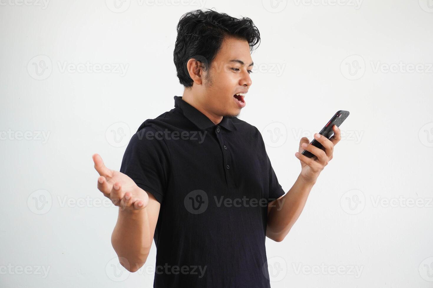 young asian man wearing black polo t shirt isolated on white background with empty space open arms and communicating talking on mobile phone photo