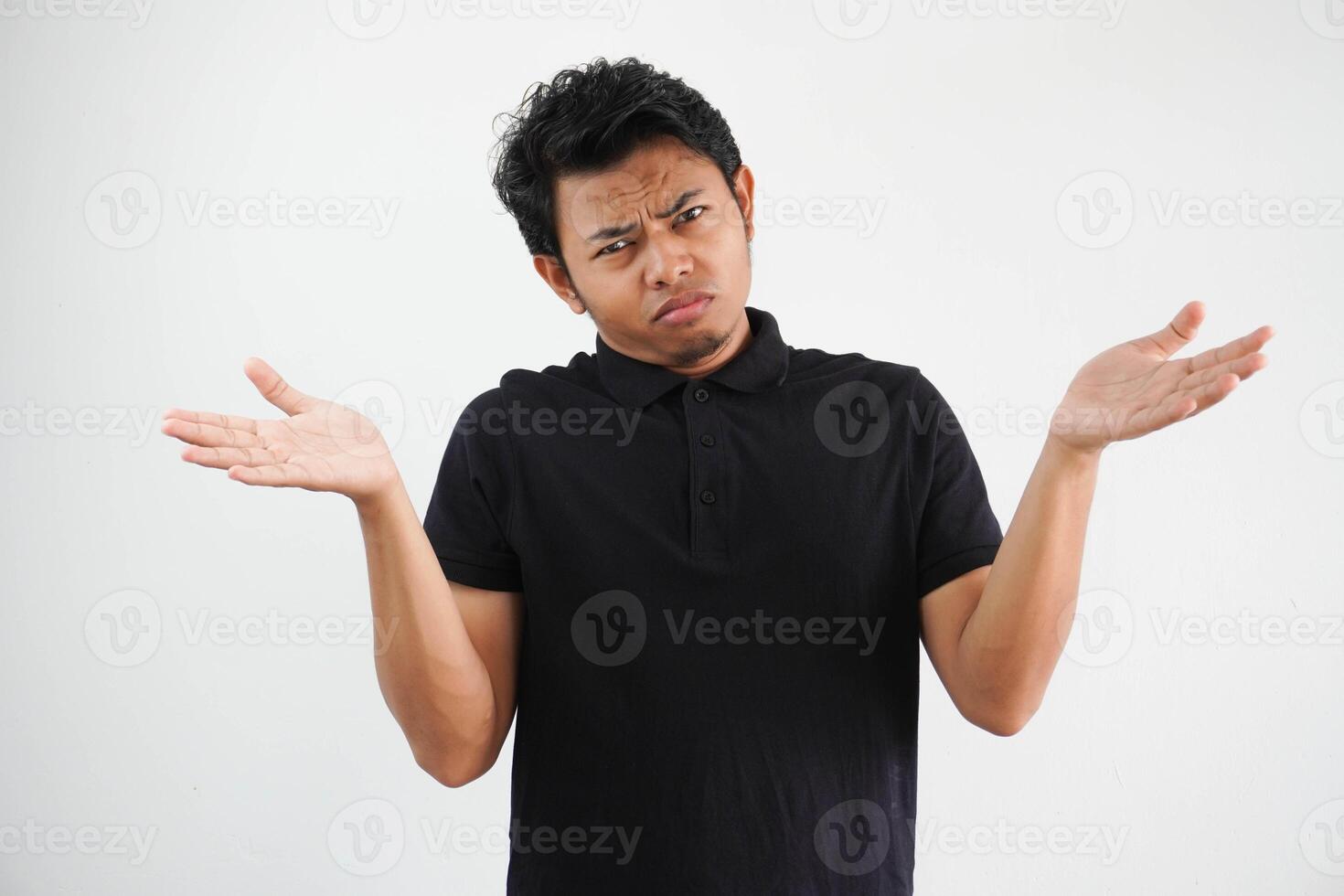 Portrait of handsome young asian man confused puzzled man shrugging shoulders wearing black polo t shirt isolated over white background photo