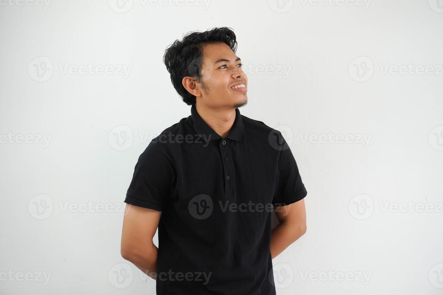 sonriente actitud joven asiático hombre mirando a el arriba lado vistiendo negro polo t camisa aislado en blanco antecedentes foto