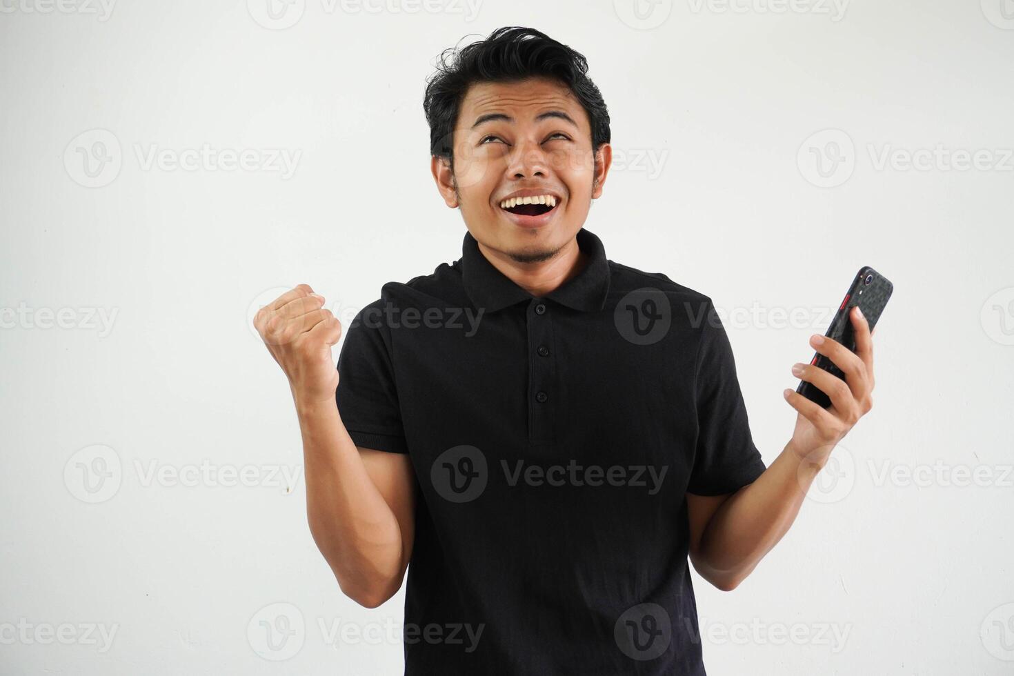 Excited happy young asian man winner feeling joy using smartphone winning lottery game, betting, getting cash back online gift in mobile app message holding cell phone isolated on white background. photo