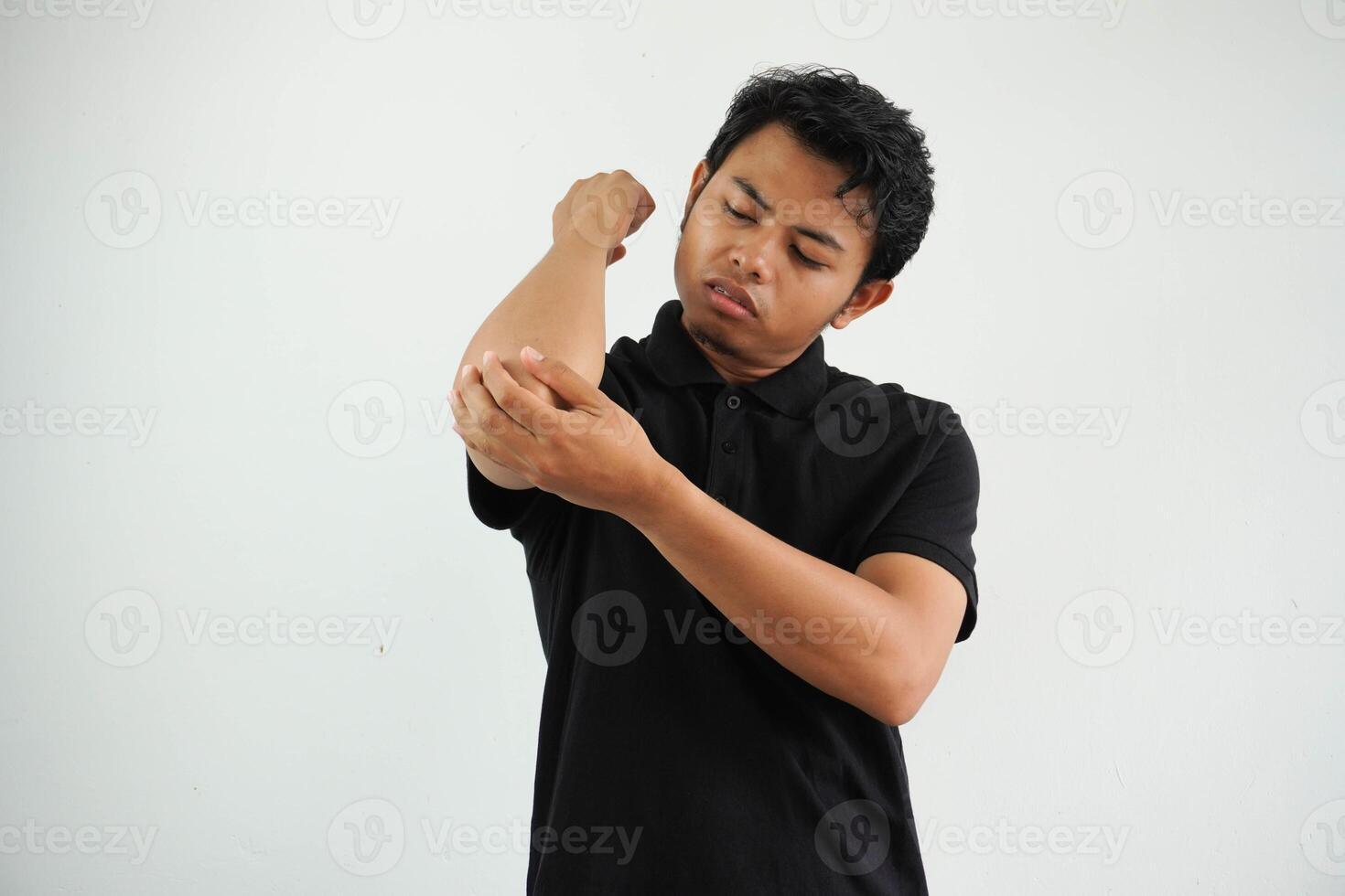 young Asian man massaging elbow, suffering after a bad movement, wearing black polo t shirt isolated on white background photo