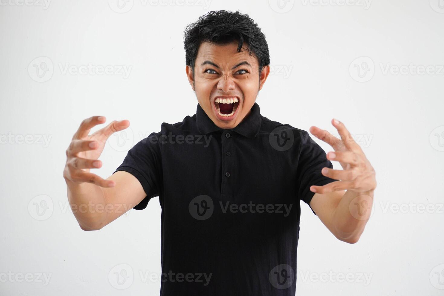Portrait of angry pensive crazy Asian young man screaming wearing black polo t shirt isolated on white background photo
