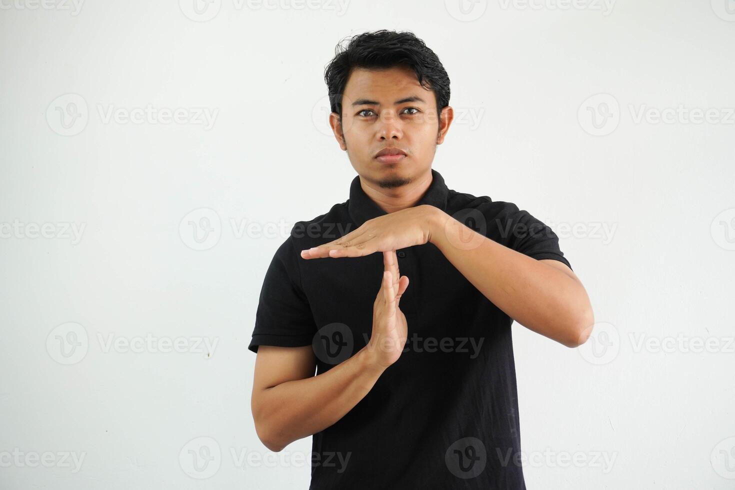 young asian man in black polo t shirt, studio shot on white backdrop showing a timeout gesture. photo