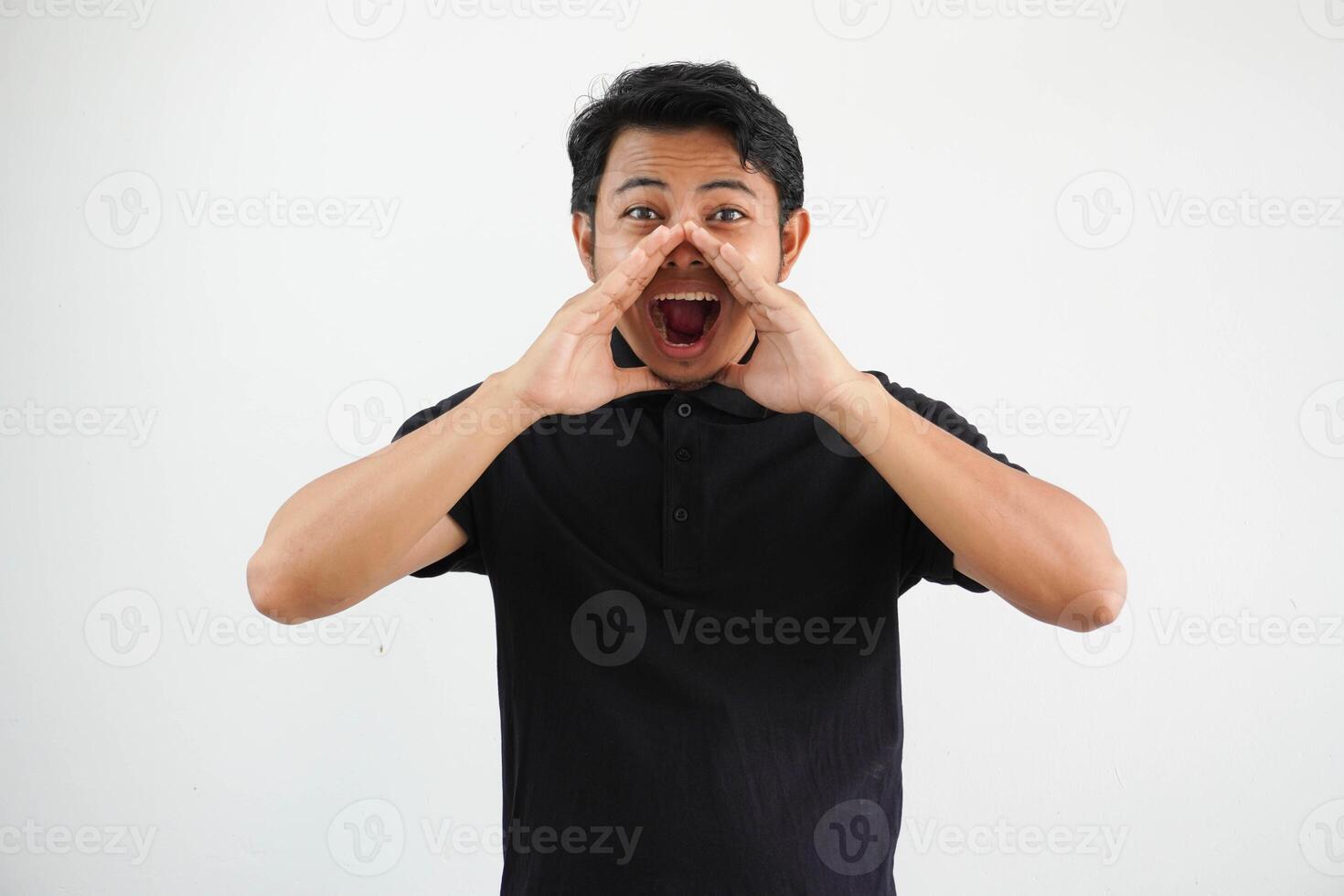 Young Asian man shouting to front with excited face expression wearing black polo t shirt isolated on white background photo