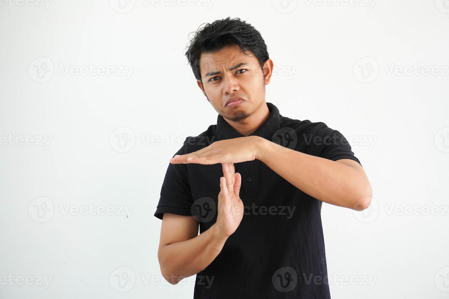 young asian man in black polo t shirt, studio shot on white backdrop showing a timeout gesture. photo