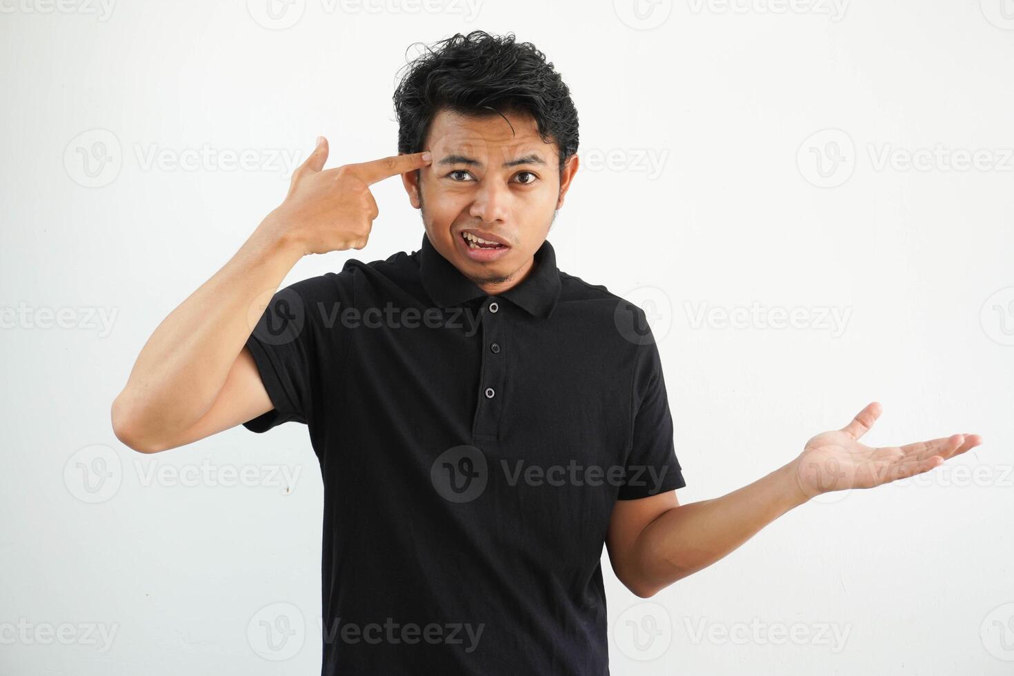 young asian man posing on a white backdrop holding and showing a product on hand, wearing black polo t shirt. photo