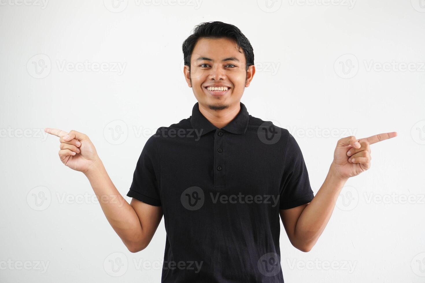 young asian man smiling at camera with both hand pointing to the right and left direction wearing black polo t shirt isolated white background photo