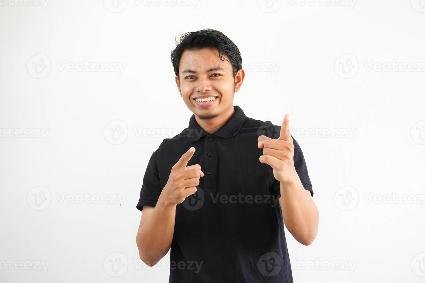 joven asiático hombre sonriente y señalando hacia cámara vistiendo negro polo t camisa aislado en blanco antecedentes. foto