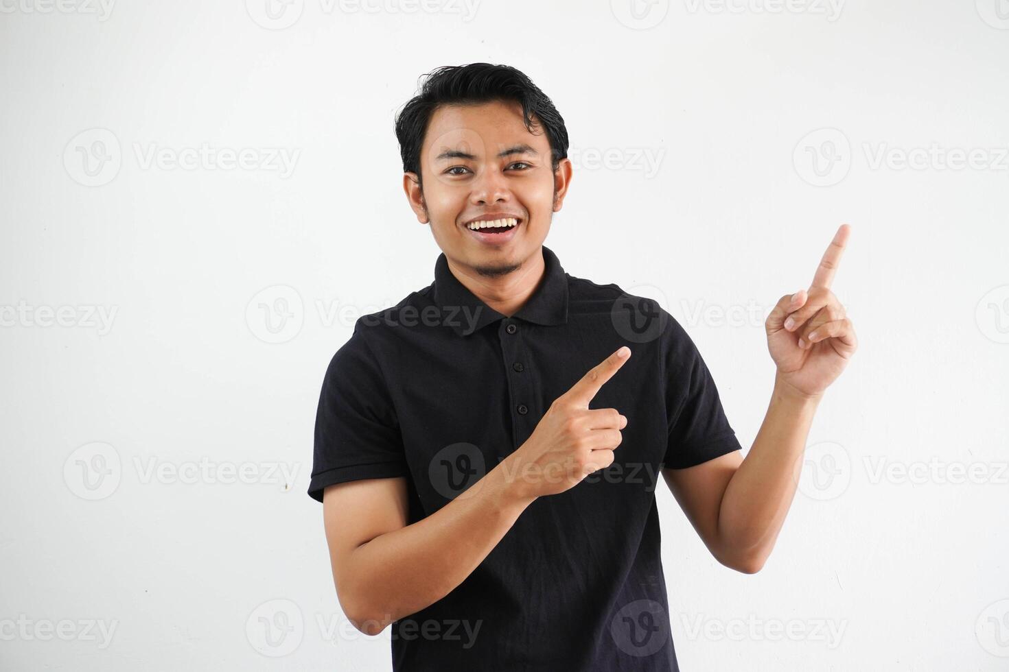 excited young asian man smiling confident with both hand pointing to the left side wearing black polo t shirt isolated white background photo