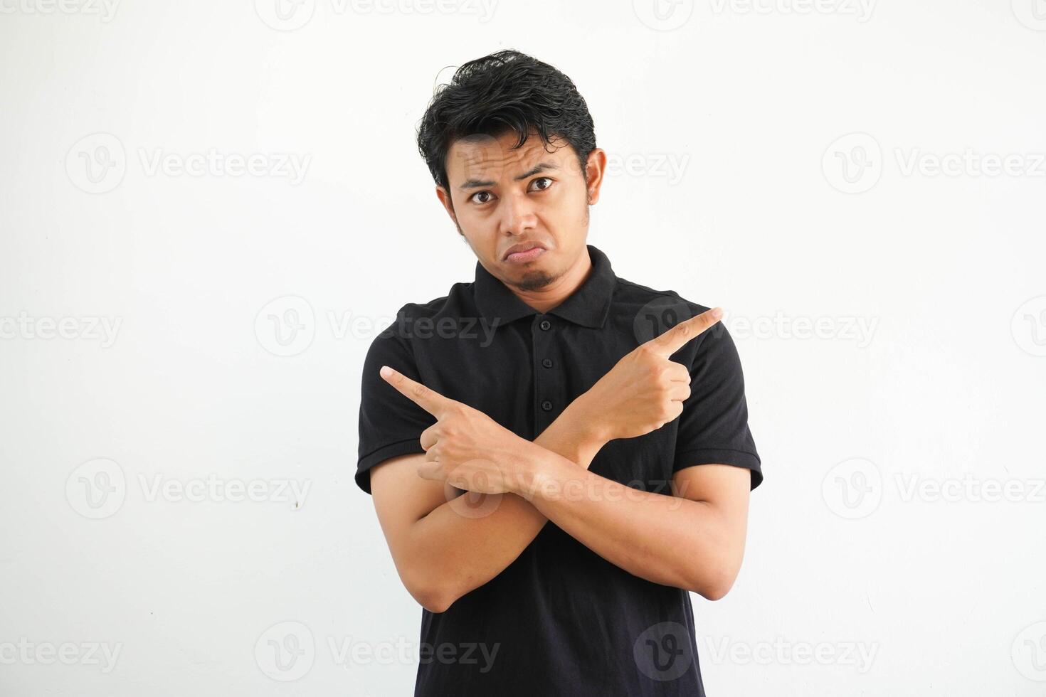 young asian man in a black polo, white studio points sideways, is trying to choose between two options. photo