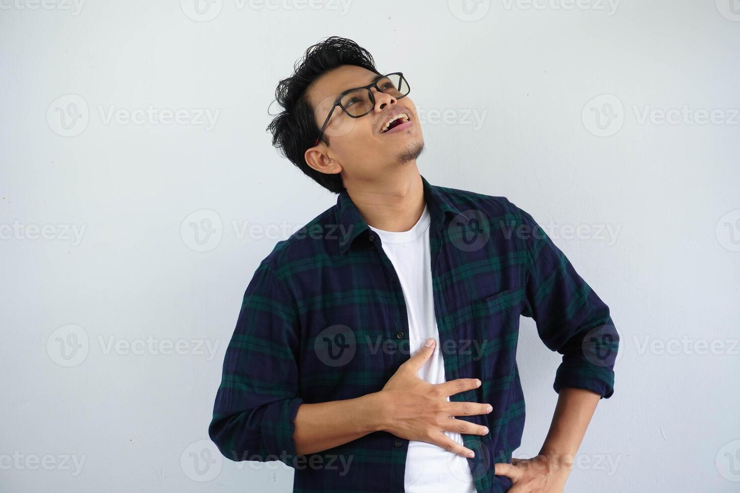 young asian man touches his belly with a relieved expression that he is full after eating isolated on white background. photo