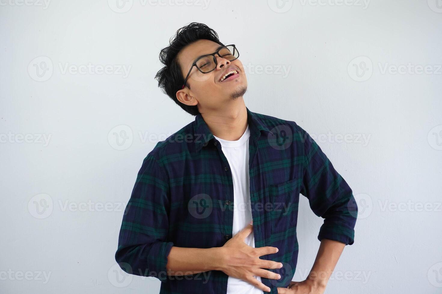 young asian man touches his belly with a relieved expression that he is full after eating isolated on white background. photo