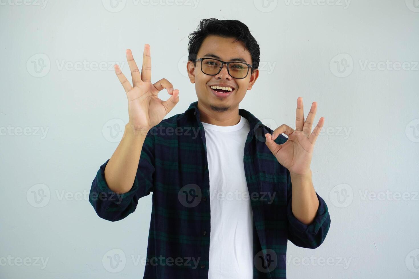 young asian man showing excited face expression while giving two OK finger sign isolated on white background. photo