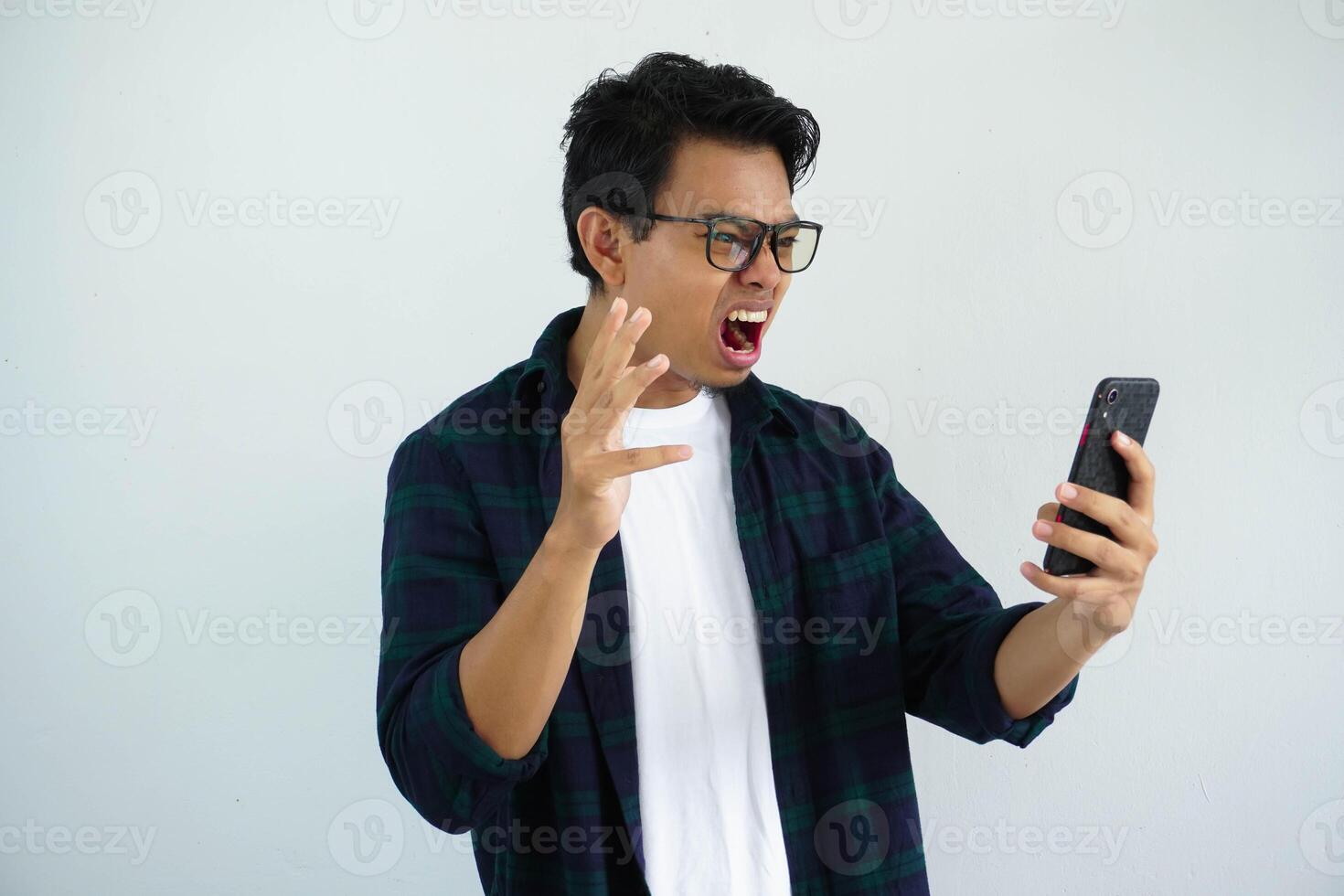 young asian man showing rage expression when looking to his cellular phone isolated on white background. photo