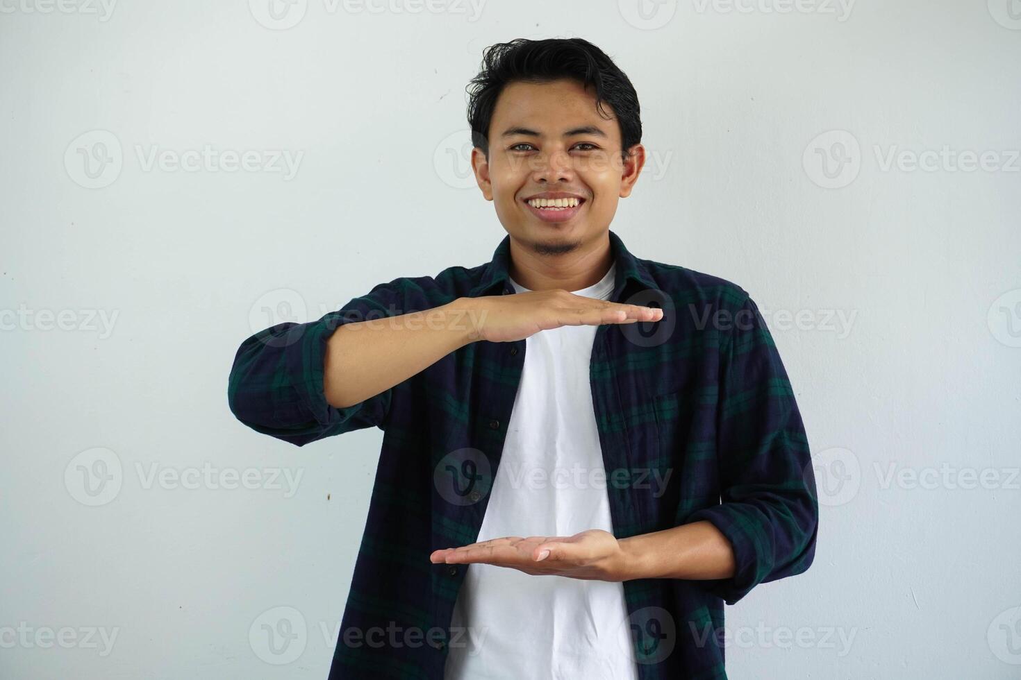 joven asiático hombre en contra un blanco estudio antecedentes participación alguna cosa con ambos manos, producto presentación. foto