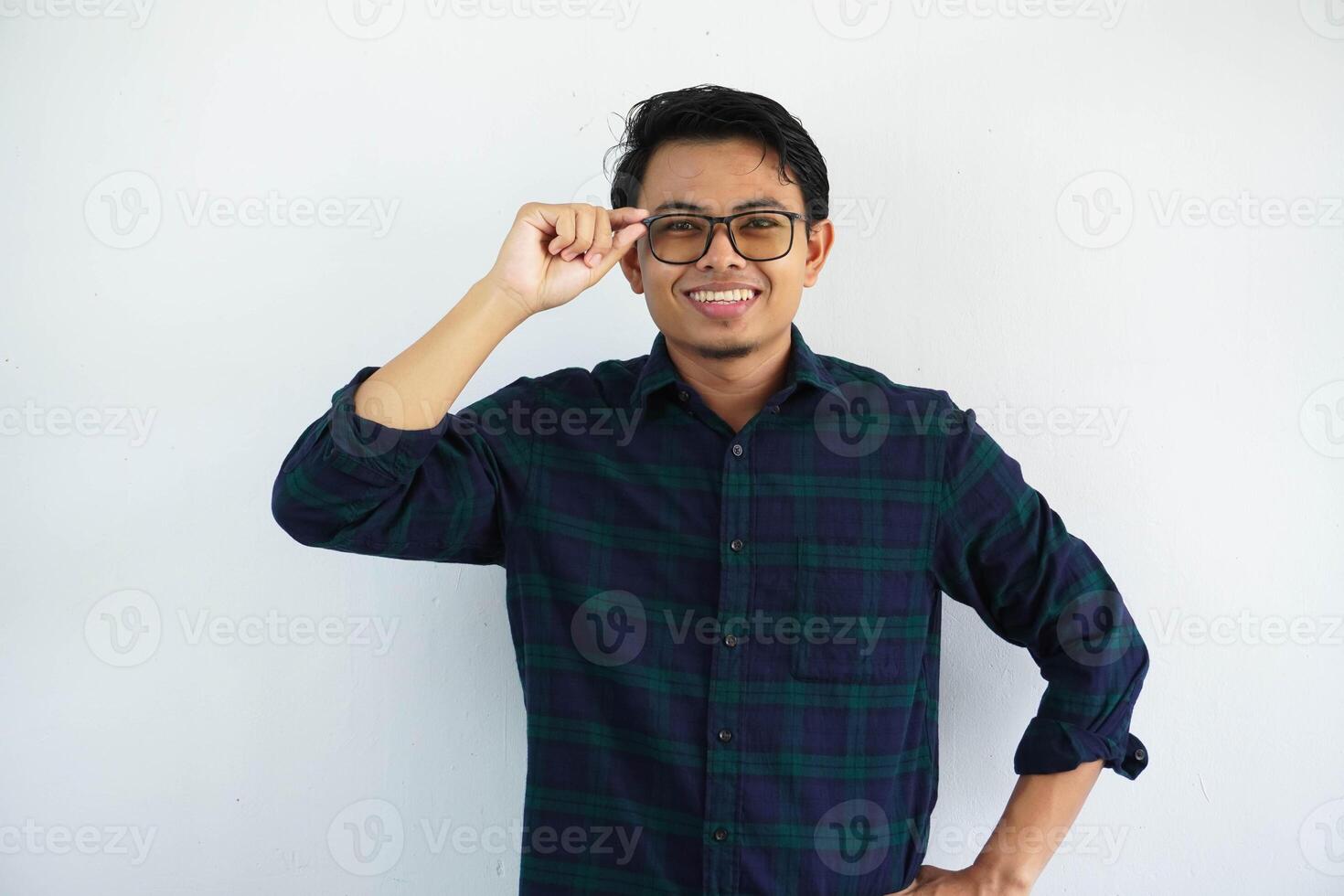 smiling or happy young asian man with hand touching his glasses frame isolated on white background. photo